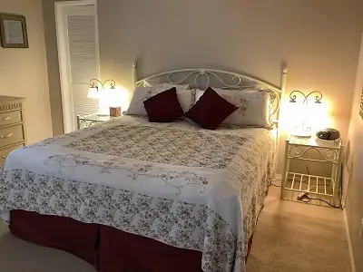 master bedroom with king bed, white comforter and 2 red pillows